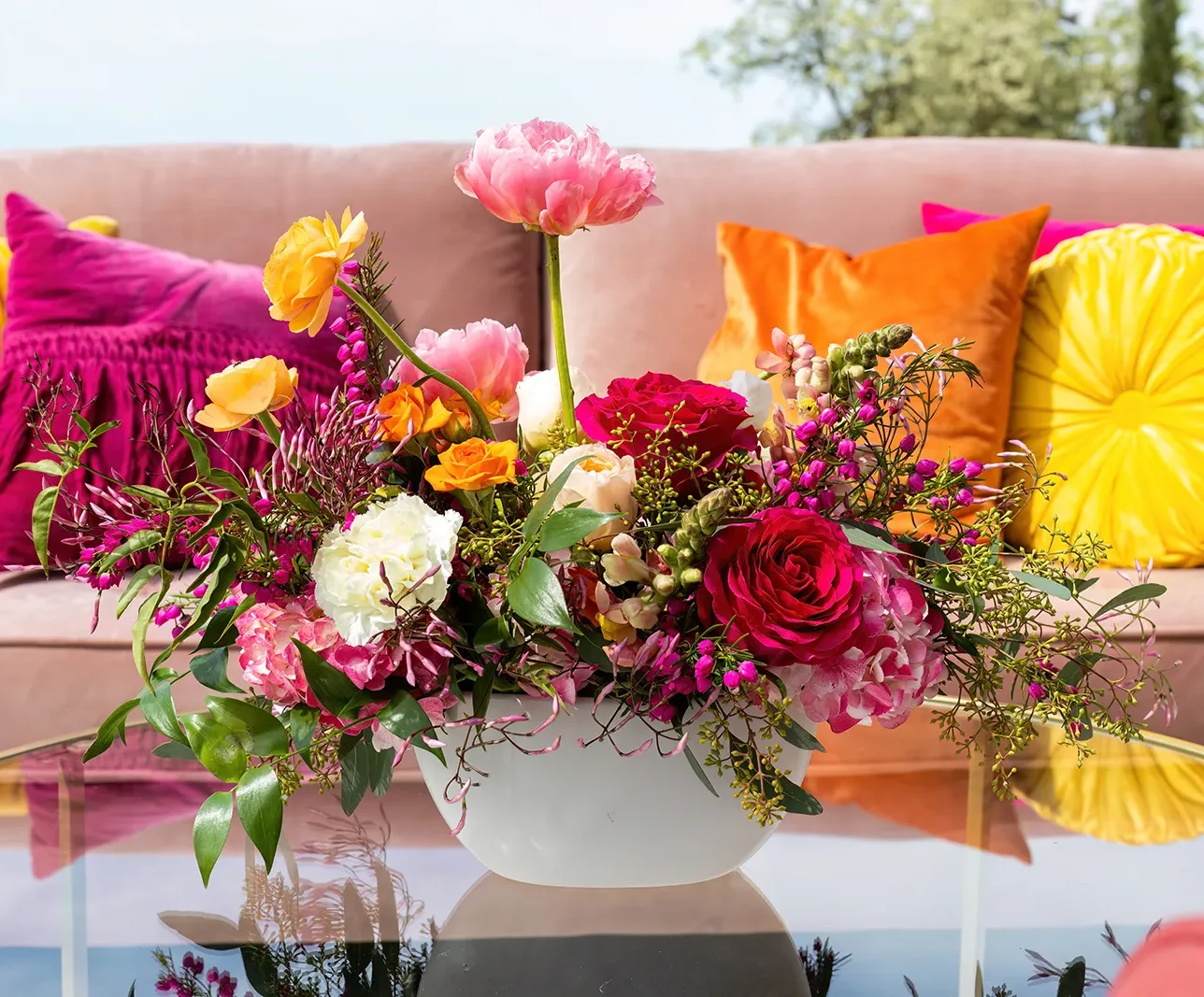 bright magenta, yellow, and white floral centerpiece is low profile vase